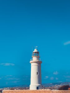 a white lighthouse with a blue sky in the background
