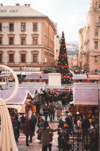 A Giant Christmas Tree Near a Market with Shoppers