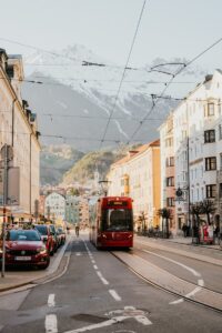 Scenic view of a tram in Innsbruck with stunning snow-capped mountains in the background.