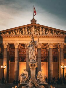 Illuminated statue of Athena in front of the Austrian Parliament Building at dusk.