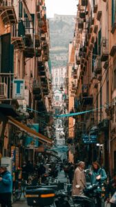 a narrow city street lined with buildings and people