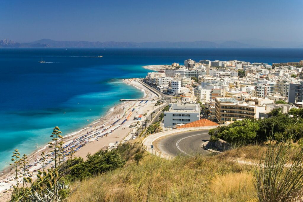 Stunning aerial view of Rhodes, Greece with its beautiful beach and vibrant cityscape under a clear blue sky.