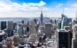 A stunning aerial view of New York City's skyline featuring the iconic Empire State Building under a bright blue sky.