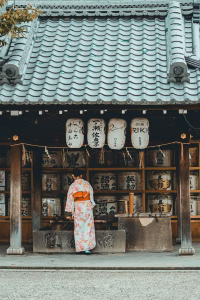 woman wearing orange and white kimono dress standing near the house