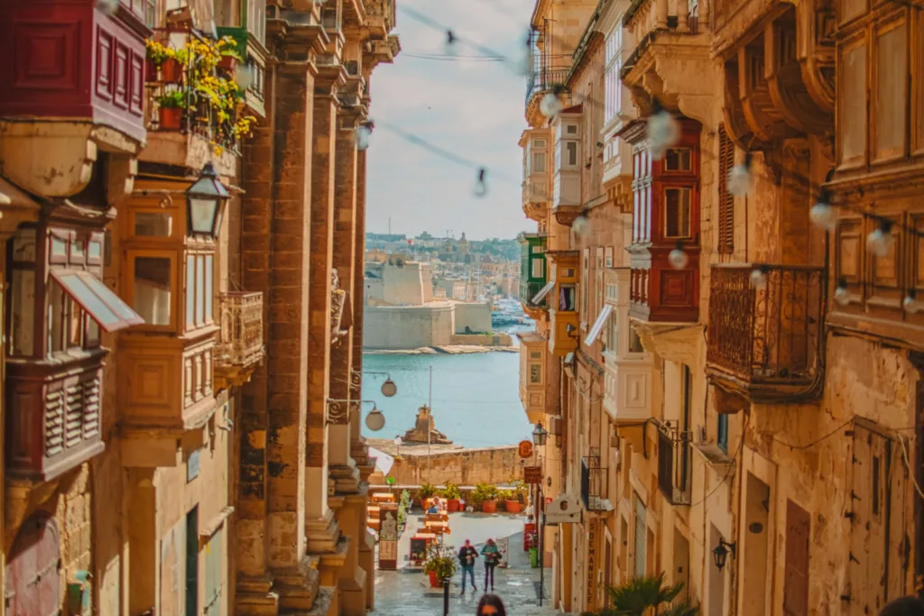 A narrow street in Valletta with traditional wooden balconies overlooking the Grand Harbour
