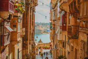 A narrow street in Valletta with traditional wooden balconies overlooking the Grand Harbour